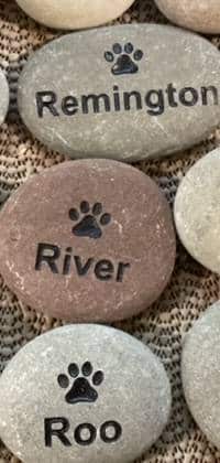Three small engraved name rocks with pet names, Remington, Rover, Roo. Each with graphic of a paw print.