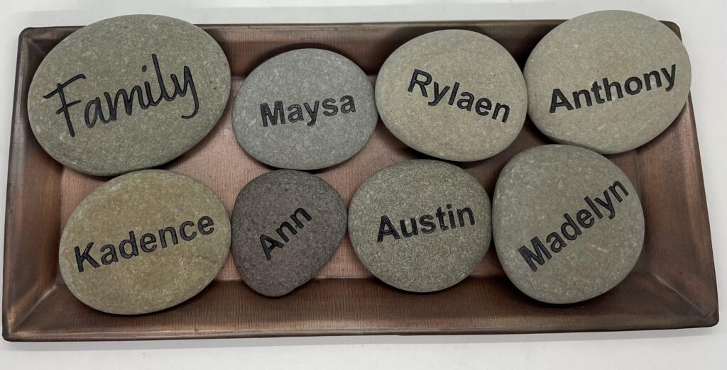 A wood box full of eight engraved rocks that have names of everyone in the family.