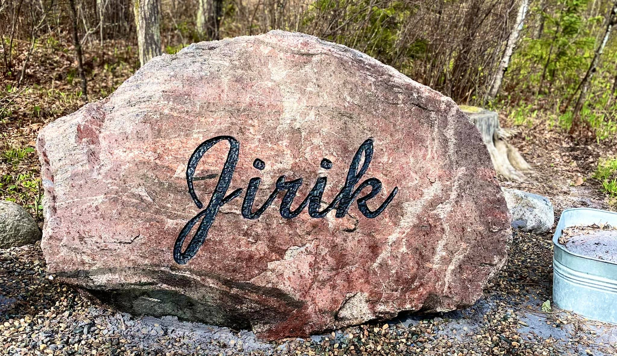 Large red stone engraving that says, Jirik. Used as a property marker.