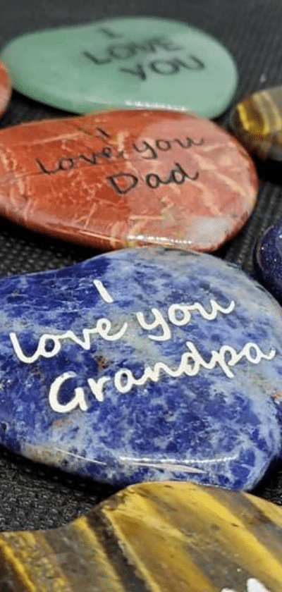 Small polished heart shaped engraved stones in colors green, red, and blue. Engraved with I love you grandpa, Ilove you dad, I love you