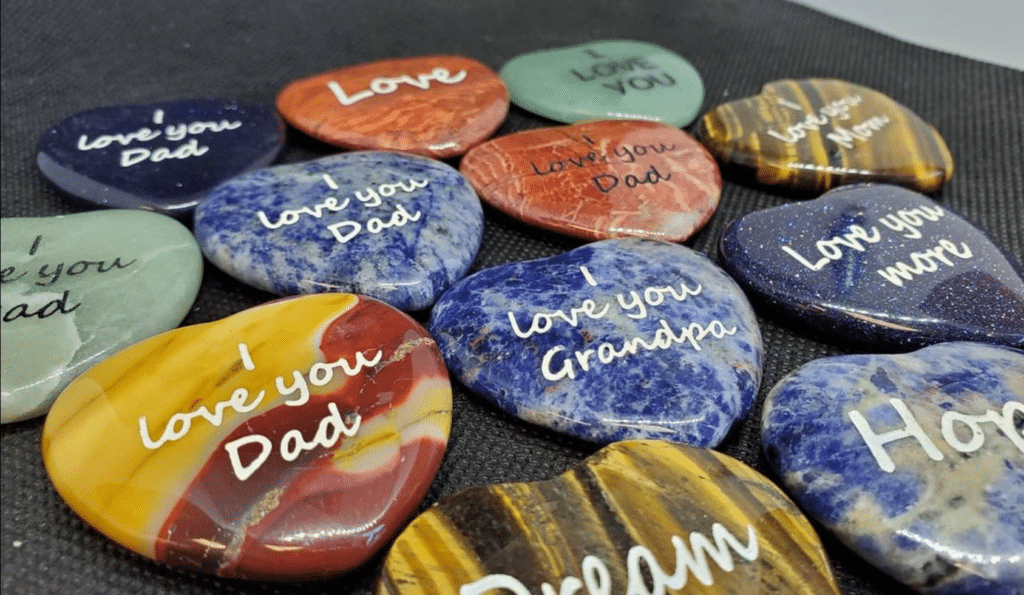 Small engraved and polished heart shaped stones. in colors, blue, red, tiger eye, and purple. Includes text I love you
