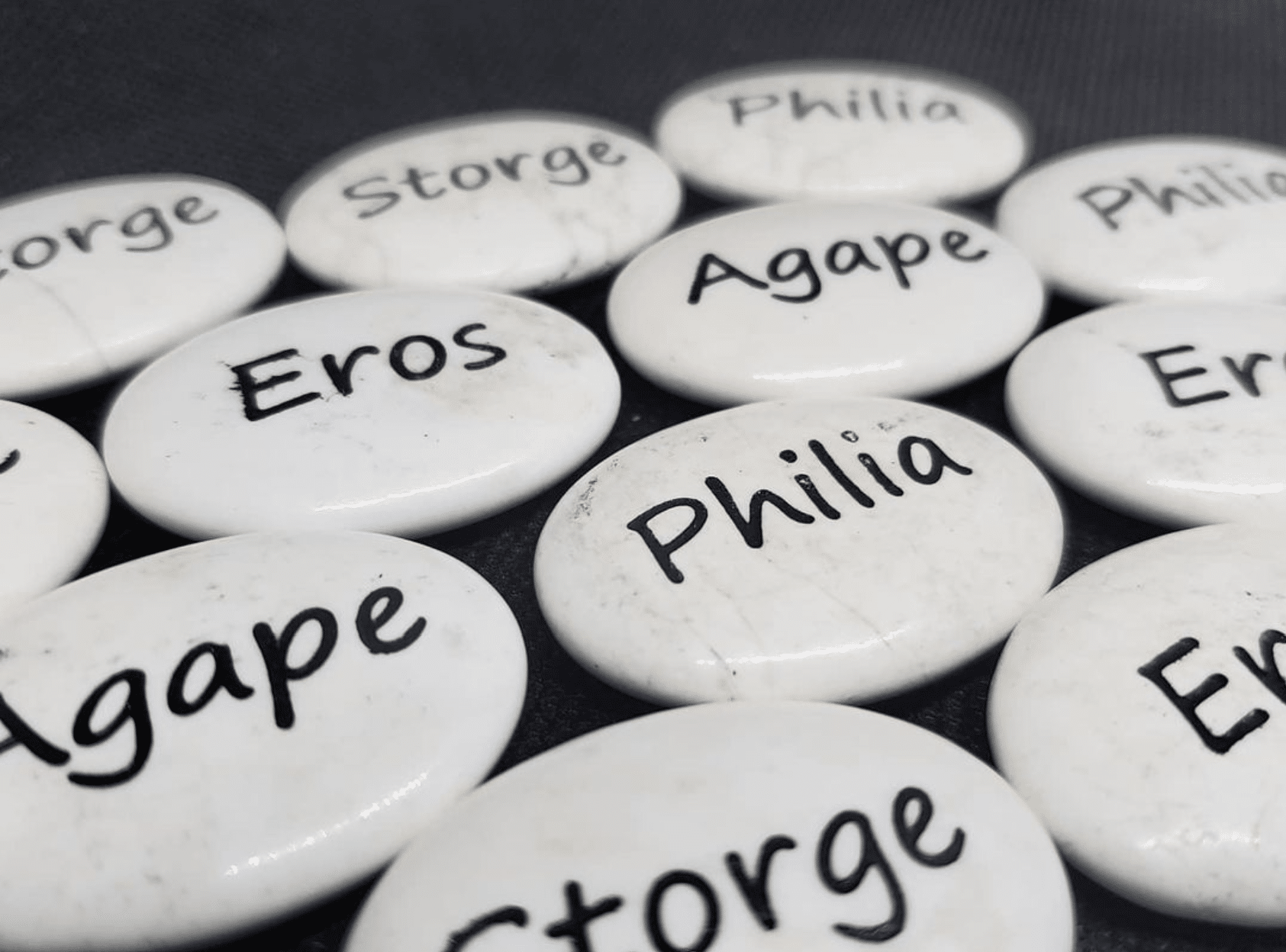 White polished engraved stones that have black text Eros, Philia, Agape, Philia, Storage