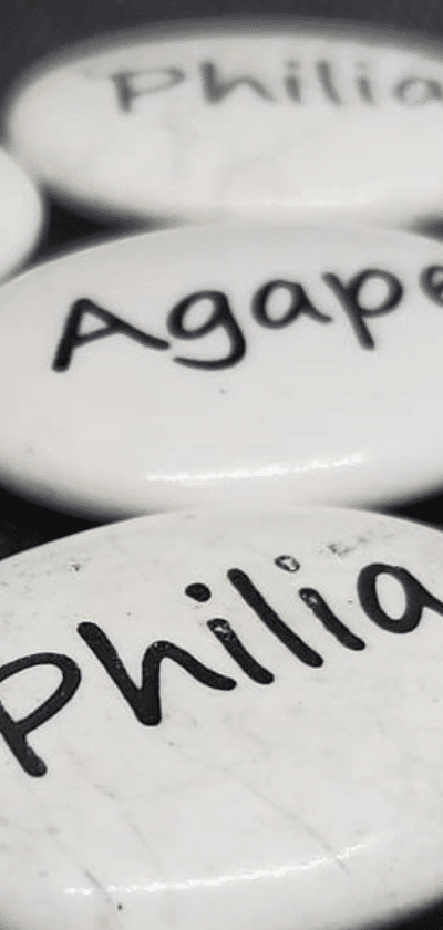 Two white stones are depicted. One reads Agape and the other reads Philia.