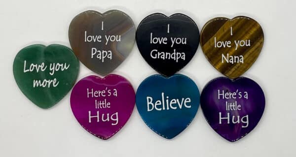 Heart shaped engraved stones in colors pink, blue, green, black, purple, and white. Most engraved with I love you.