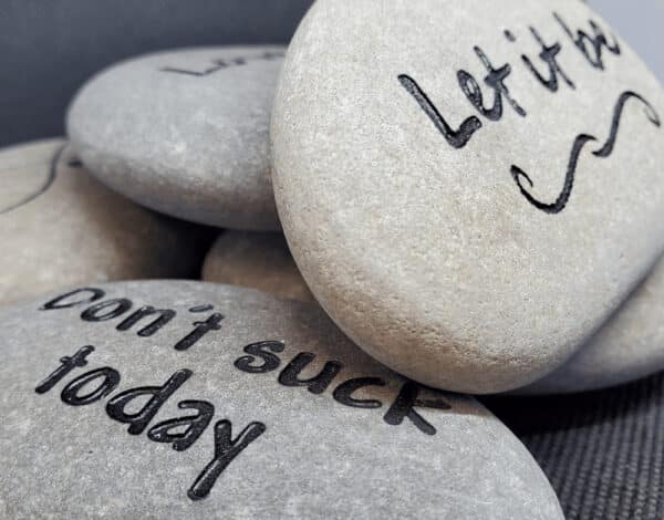 White phrase rocks with the engravings "Don't suck today" and "Let it be"