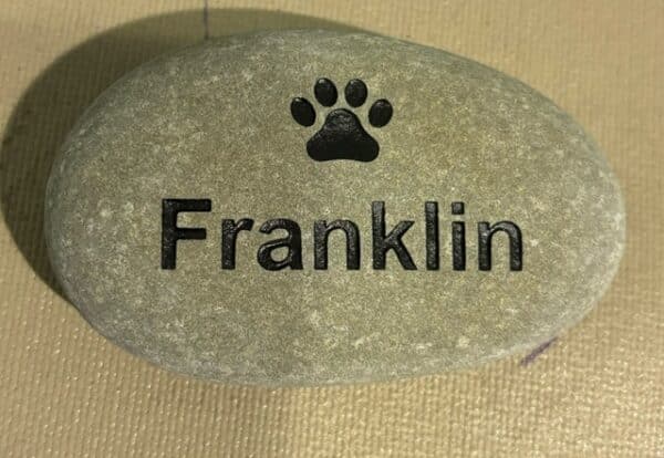 The name Franklin is engraved on a stone with a paw print engraving above the name.
