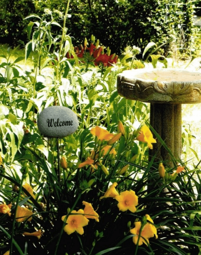 engraved garden stones in the garden next to a bird water bath